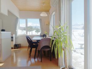 a dining room with a table and chairs and a window at Hillview cottage Sanfurano in Kami-furano
