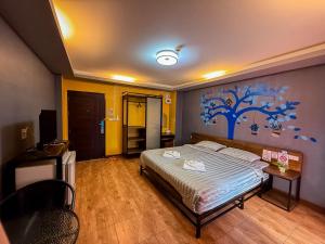 a bedroom with a bed with a blue tree mural on the wall at Nangnon Hill Hug Hotel in Ban Pa Muat