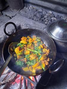Eine Pfanne mit Essen gart auf dem Grill in der Unterkunft Riverside hostel in Ghanpokhara