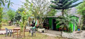 ein Gewächshaus mit Stühlen, einem Tisch und Bäumen in der Unterkunft Riverside hostel in Ghanpokhara