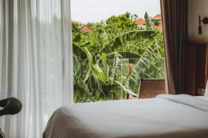 a room with a bed and a window with a view at Suom Apartments and Villas Canggu in Canggu