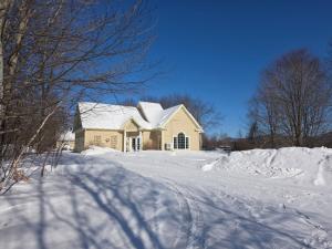 a house in the snow with a snow covered driveway at Domaine des sentiers in Mansonville