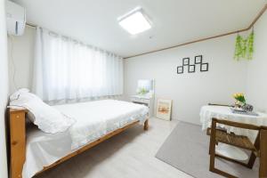 a white bedroom with a bed and a table at Tov Stay Atti in Pyeongtaek