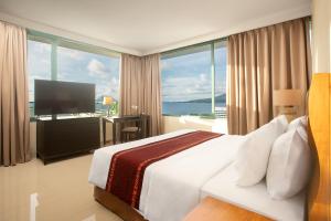 a hotel room with a bed and a view of the ocean at Aryaduta Manado in Manado