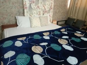 a bed with a blue and white blanket on it at Urban Cozy 2 bhk in Ghaziabad