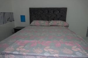 a bed with a pink bedspread and a black headboard at San Cristóbal Surf House II in San Cristóbal