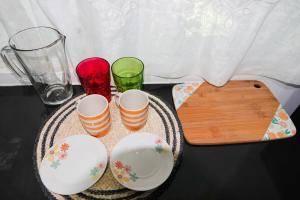 a table with four cups and a wooden cutting board at San Cristóbal Surf House II in San Cristóbal