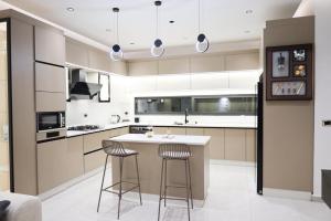 a kitchen with a island and two bar stools at Amora Villa in Al Rama