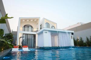 a villa with a swimming pool in front of a house at Amora Villa in Al Rama