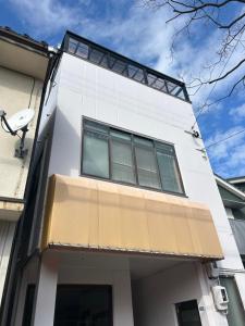 a white building with a window on it at Toolate Guesthouse Toyama in Toyama