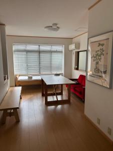 a living room with a table and a red couch at Toolate Guesthouse Toyama in Toyama
