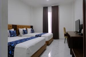 a hotel room with two beds and a desk at Grand Elhajj Banten in Tjipondoh Tiga