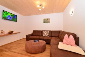 a living room with a brown couch and a stool at Landhof Müller in Wertach