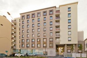 a large building with cars parked in front of it at Séjours & Affaires Paris Bagneux in Bagneux
