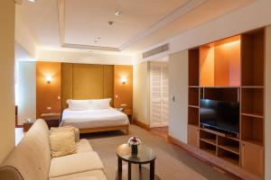 a hotel room with a bed and a flat screen tv at Centara Hotel Hat Yai in Hat Yai