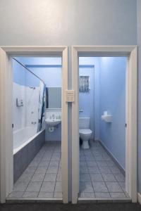 a bathroom with a toilet and a tub and a sink at Zen Hostel in Townsville