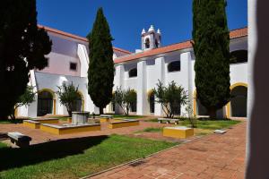 Un gran edificio blanco con árboles delante. en Pousada Convento de Beja, en Beja