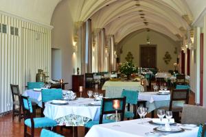 un comedor con mesas blancas y sillas azules en Pousada Convento de Beja, en Beja