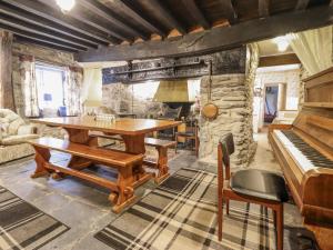 a room with a wooden table and a piano at Cynfal Fawr in Blaenau-Ffestiniog