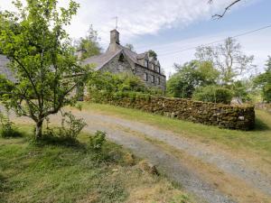 an old house with a stone wall and a dirt road at Cynfal Fawr in Blaenau-Ffestiniog