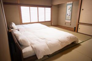 a large white bed in a room with a window at 響-Garden House- in Toyonaka