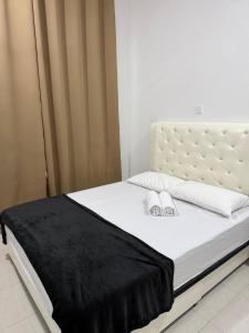 a white bed with a black blanket on it at Homestay Aydan at Kijal Kemaman in Cukai