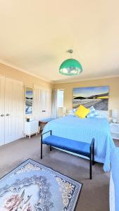 a large bedroom with a blue bed and a couch at Beach Apartment in Papamoa