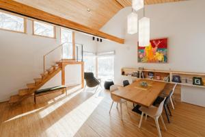 a dining room with a wooden table and a staircase at 6ty6 Vacation Home in Niseko
