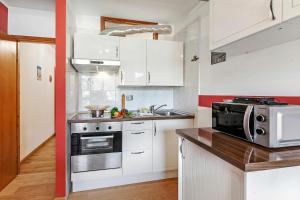 a small kitchen with white cabinets and a microwave at Studio Valleverde 26B - Happy Rentals in Sestriere