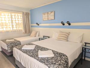 a hotel room with two beds and a window at Park Drive Motel in Kempsey