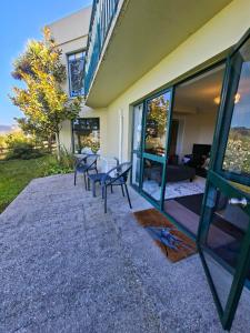 a house with a patio with benches and windows at 2-bedroom harbour view apartment with parking, 8 mins to Dunedin in Dunedin