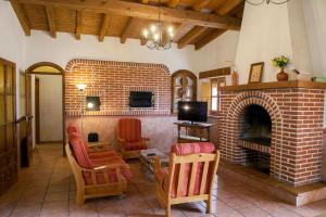 a living room with a brick fireplace and chairs at La Tahona Vieja in El Barraco