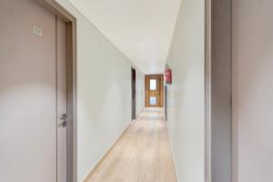 an empty hallway with white walls and wood floors at Super Townhouse DSIDC Bawana Formerly Kanhaiya Residency in Delhi +38 photos
