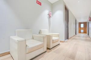 a hallway with two white chairs in a room at Super Townhouse DSIDC Bawana Formerly Kanhaiya Residency in Delhi