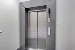 an elevator with a glass door in a building at Super Townhouse DSIDC Bawana Formerly Kanhaiya Residency in Delhi