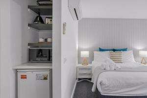 a small bedroom with a bed and a refrigerator at Bay View - Palm Springs in Lorne