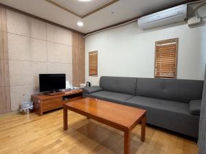 a living room with a couch and a table and a tv at Daejeon I-Hotel in Daejeon