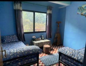 ein Schlafzimmer mit zwei Betten, einem Fenster und einem Tisch in der Unterkunft Satori Capsule Hotel in Dhulikhel