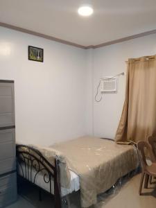 a small bedroom with a bed and a air conditioner at RMBC beds and breakfast in Badian