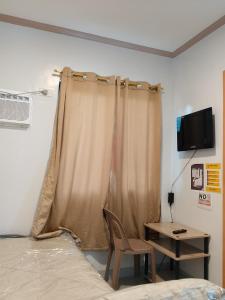 a bedroom with a curtain and a chair and a table at RMBC beds and breakfast in Badian
