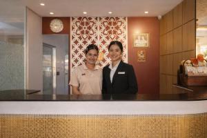 two women standing behind a counter in a restaurant at Smile Bed Hotel in Sathani Khlong Rian