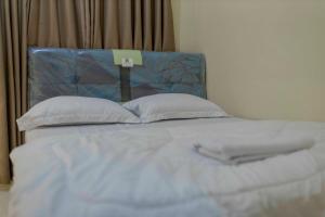 a bed with a blue headboard and two pillows at Sandik Local Stay in Midang