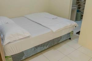 a bed with white sheets on it in a room at Sandik Local Stay in Midang