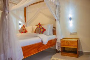 a bedroom with a canopy bed with white sheets and pillows at Shangani Hotel in Zanzibar City