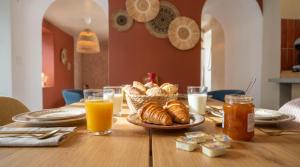a table with a plate of bread and glasses of orange juice at Suite Marrakech avec jacuzzi privatif Love Room romantique proche Toulouse in Auterive