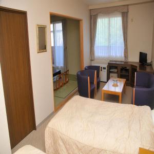 Habitación de hotel con cama, mesa y sillas en Yumoto Ginsenkaku, en Kamikawa