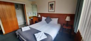 a bedroom with a large bed with two pillows at Mt Lyell Motor Inn - By Orangepete in Queenstown