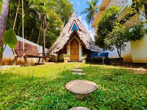 a small house with a thatched roof in a yard at Turtle Wood Cabin in Tangalle