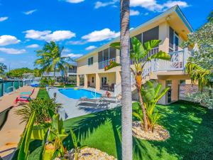 a view of a house with a swimming pool and palm trees at Paradise PalmsDockPoolKayaks GrillView! in Marathon