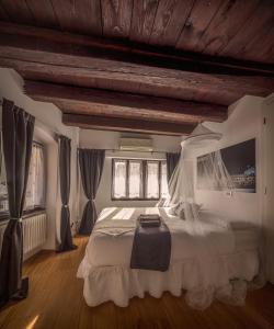 una camera da letto con un grande letto bianco con tende di B&B Gli Scorci di Trento a Trento